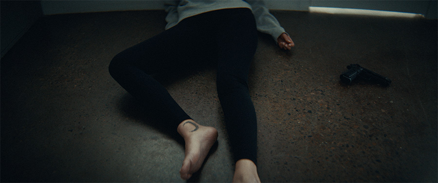 A woman laying on the floor with a gun nearby