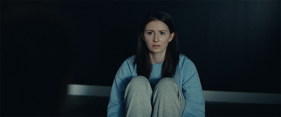 A woman wearing blue sits on the floor.