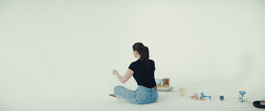 A woman sits on the floor next to dishware